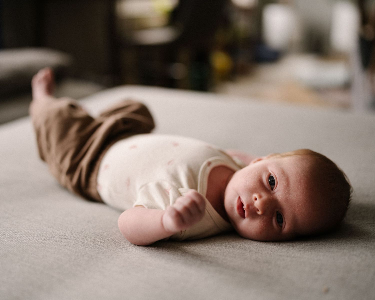 A series of artistic photographs showing a figure lying down against a neutral background in different poses.