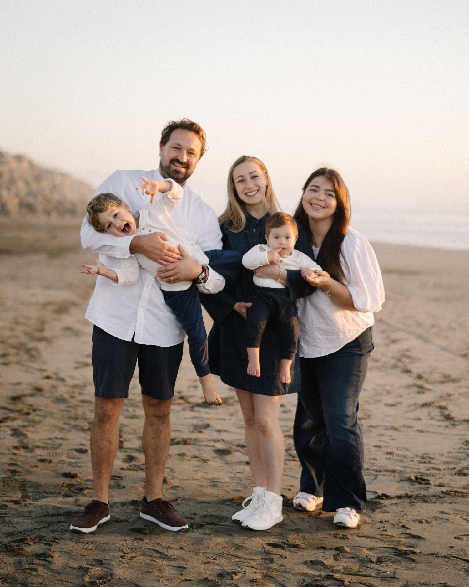 Playful family interactions on a sandy beach during golden hour.
