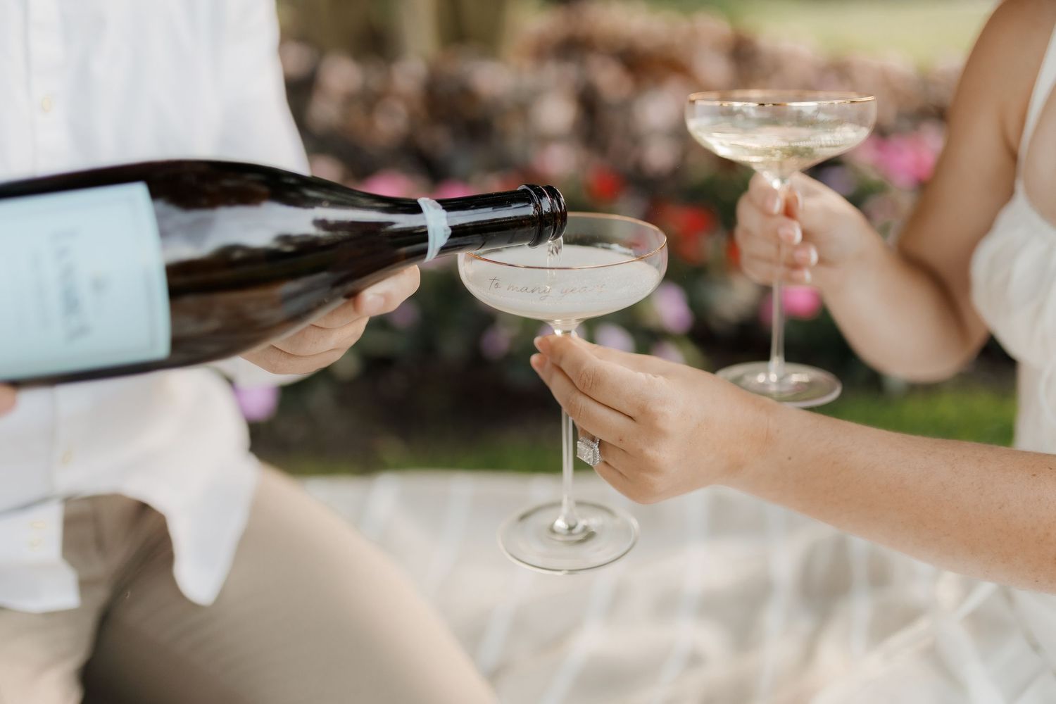 Wedding guests clink champagne glasses in an elegant outdoor celebration setting.