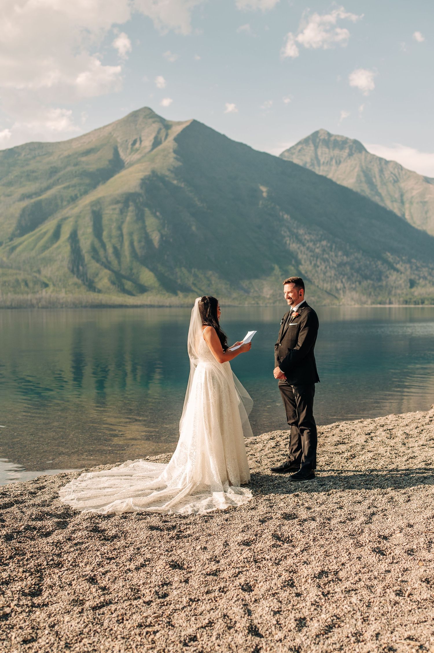 Couple exchanges vows during intimate lakeside elopement ceremony with majestic mountain peaks and turquoise water as backdrop.