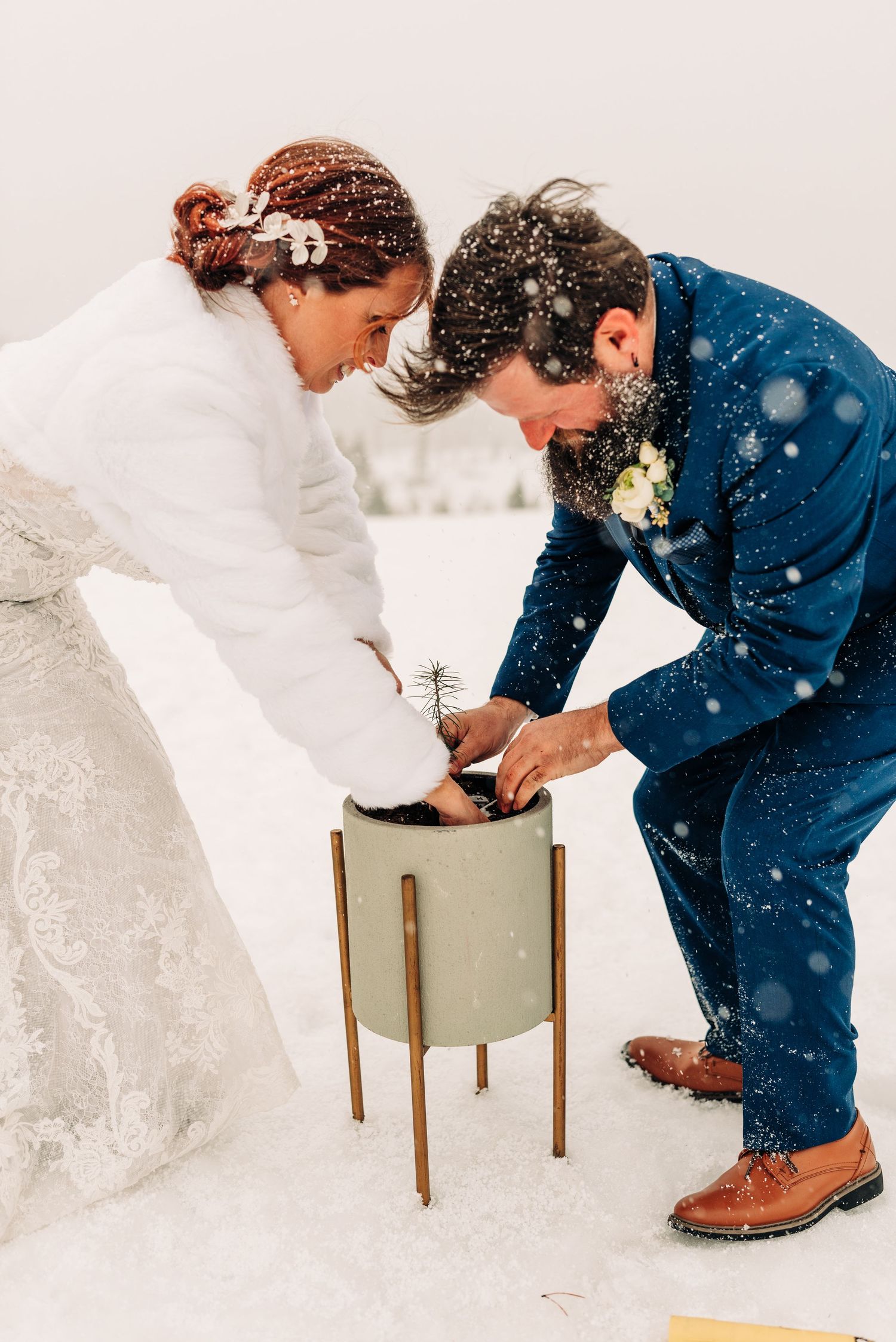 Couple performing a unity ceremony with a modern planter in the snow.