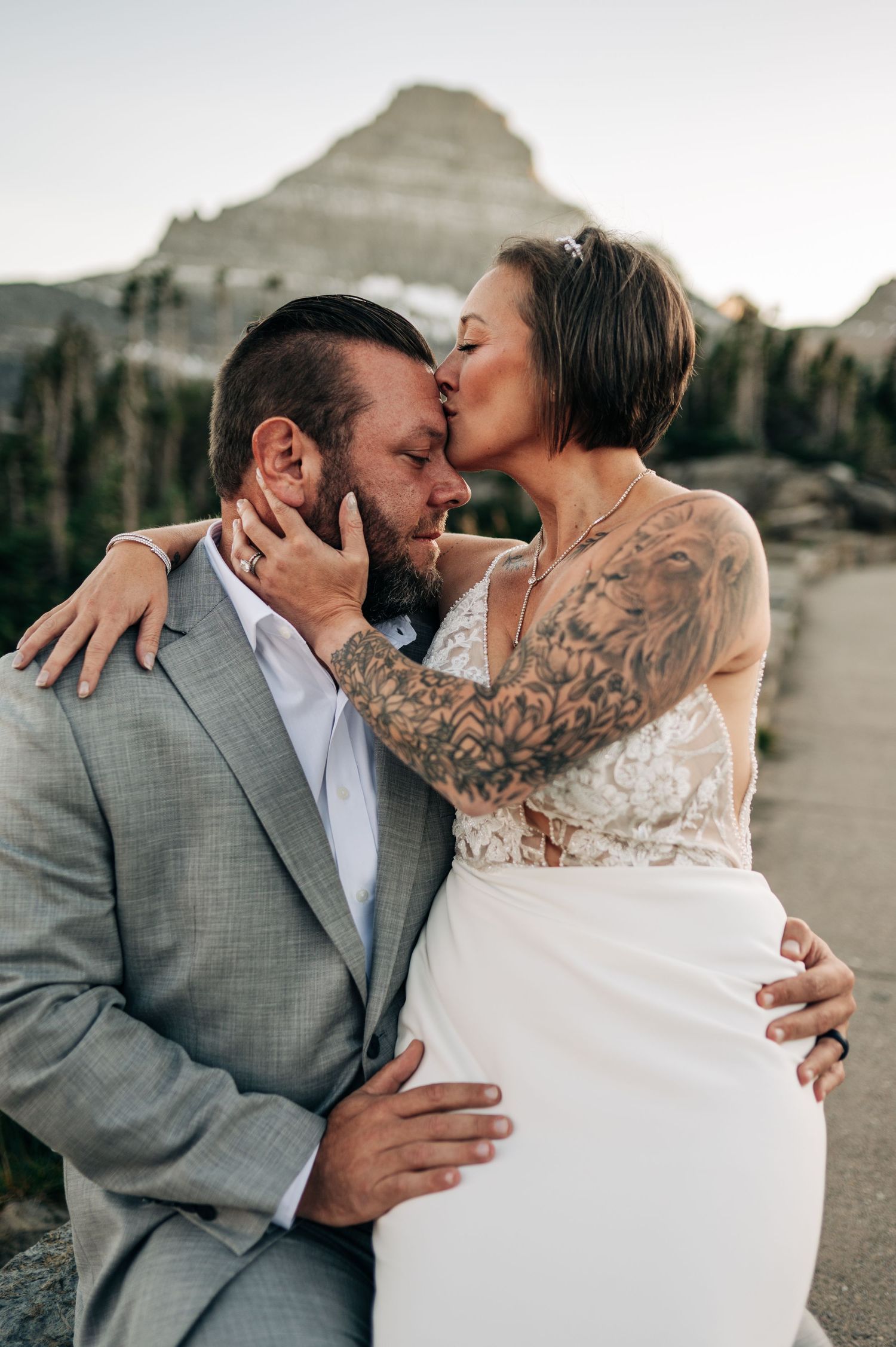 A couple in wedding attire share intimate moments against a desert mountain backdrop during their photoshoot.