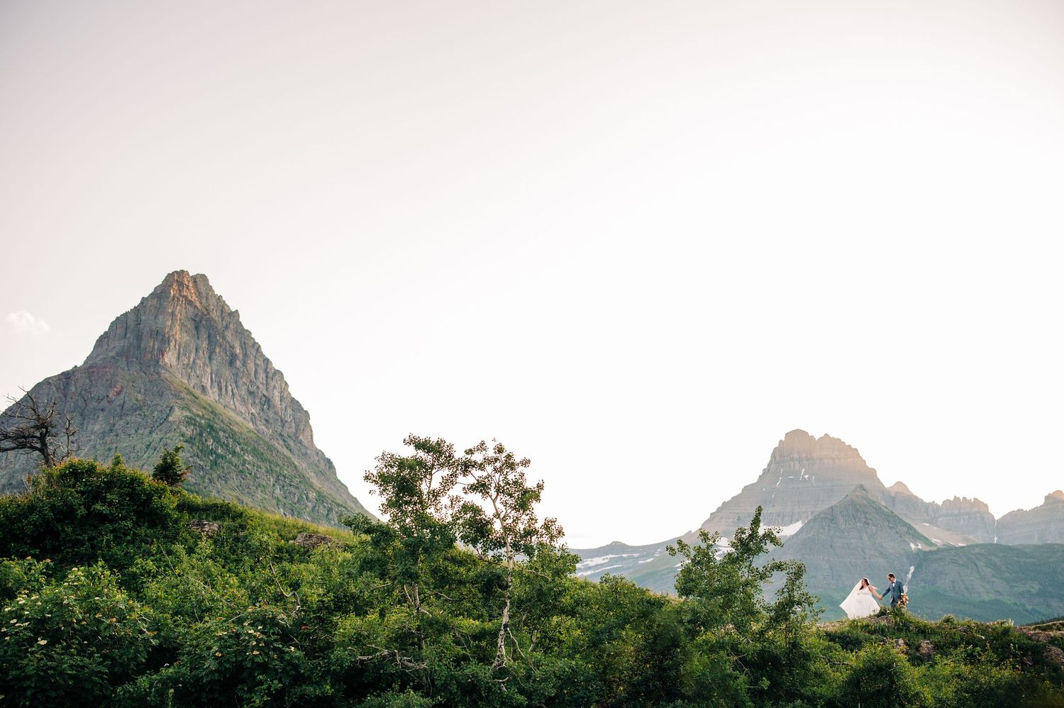 Panoramic sunset view of rugged mountain peaks and ridgelines silhouetted against a warm sky in a national park.