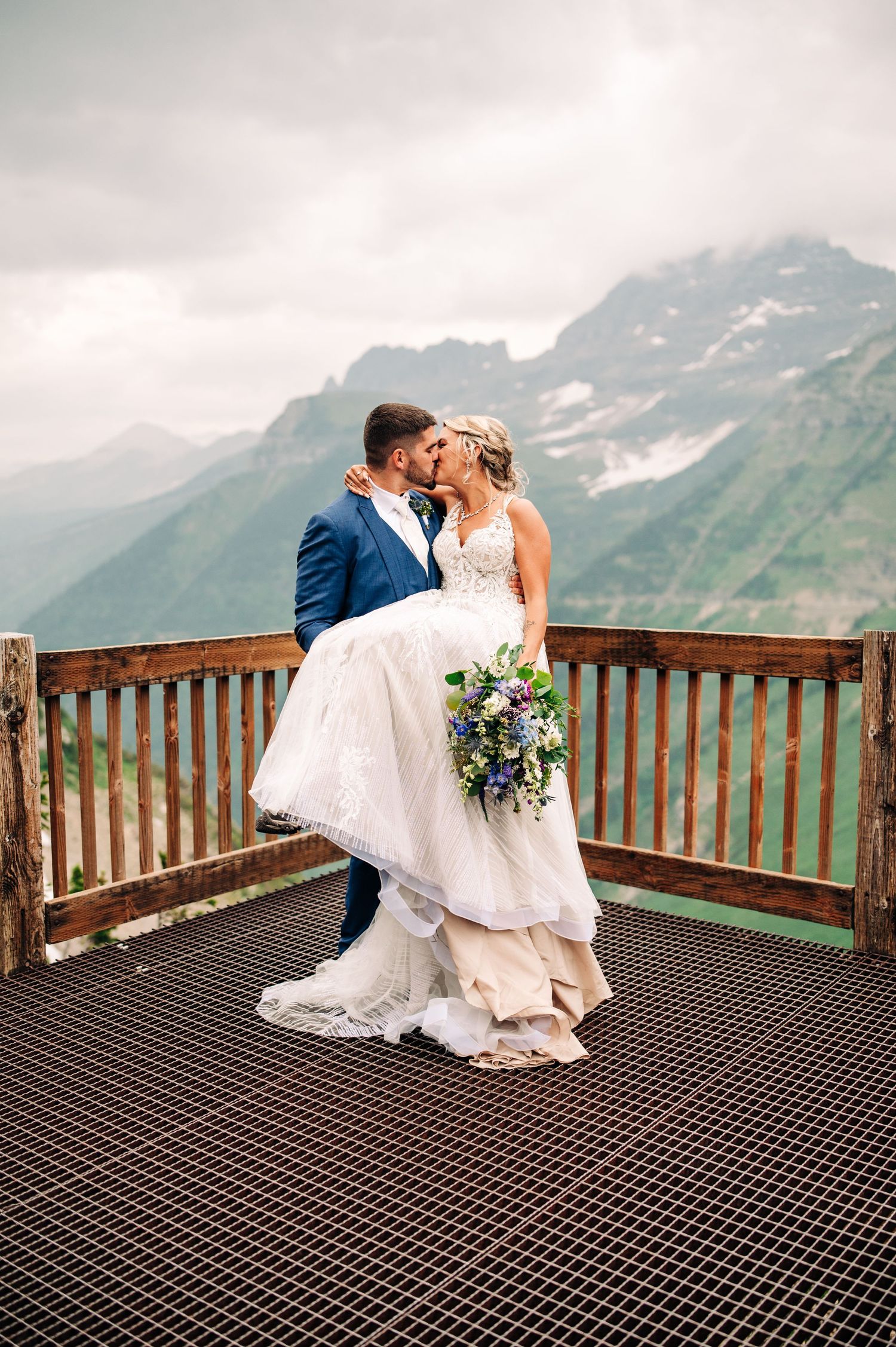 Romantic wedding moment on observation deck with stunning mountain vista in background.