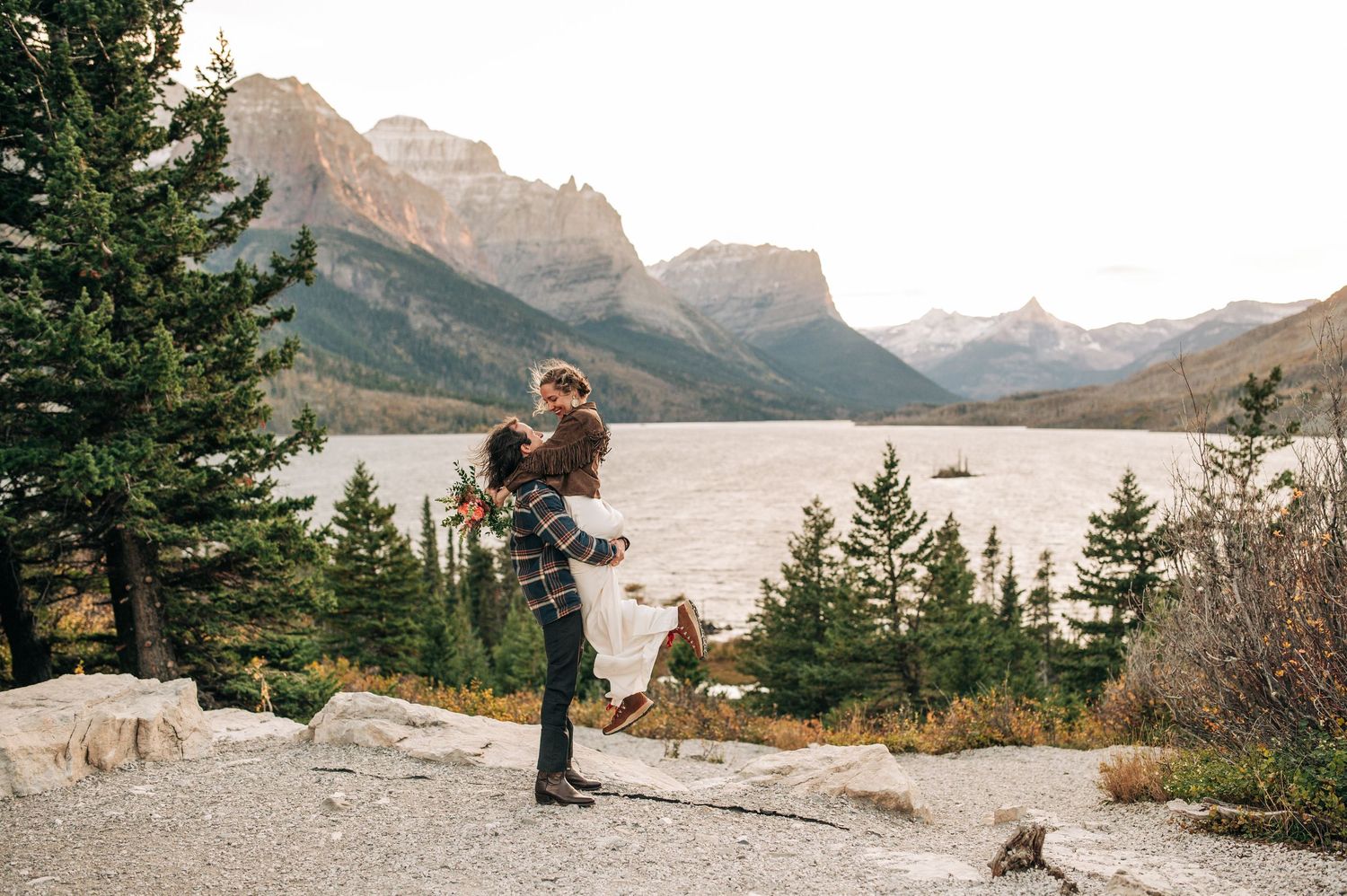 A scenic lake surrounded by mountains with evergreen trees and natural terrain in a wilderness setting.