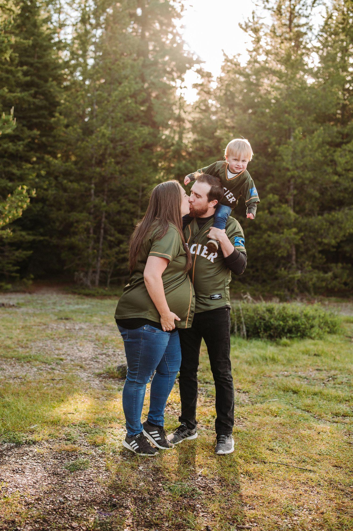 A happy family shares an intimate moment together in a forest clearing during golden hour sunset.