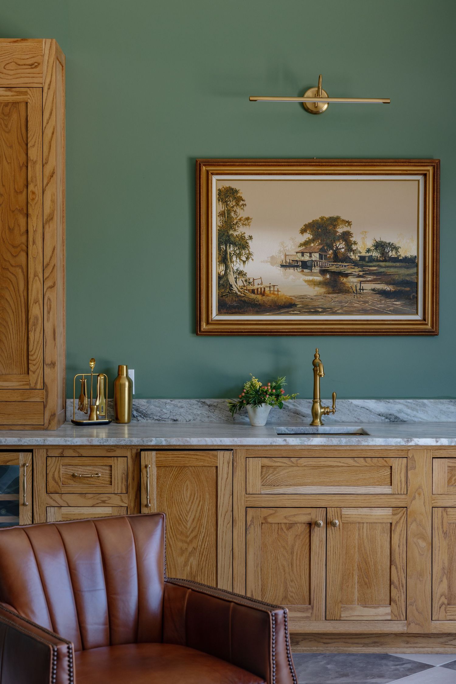 Classic dining room interior with wood paneling, teal walls, framed landscape artwork, and brown leather booth seating.