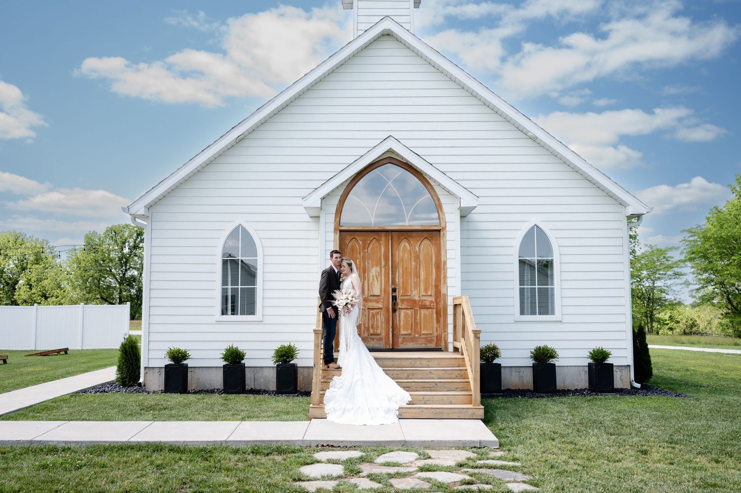 Classic white chapel with wooden doors and arched windows on sunny day.