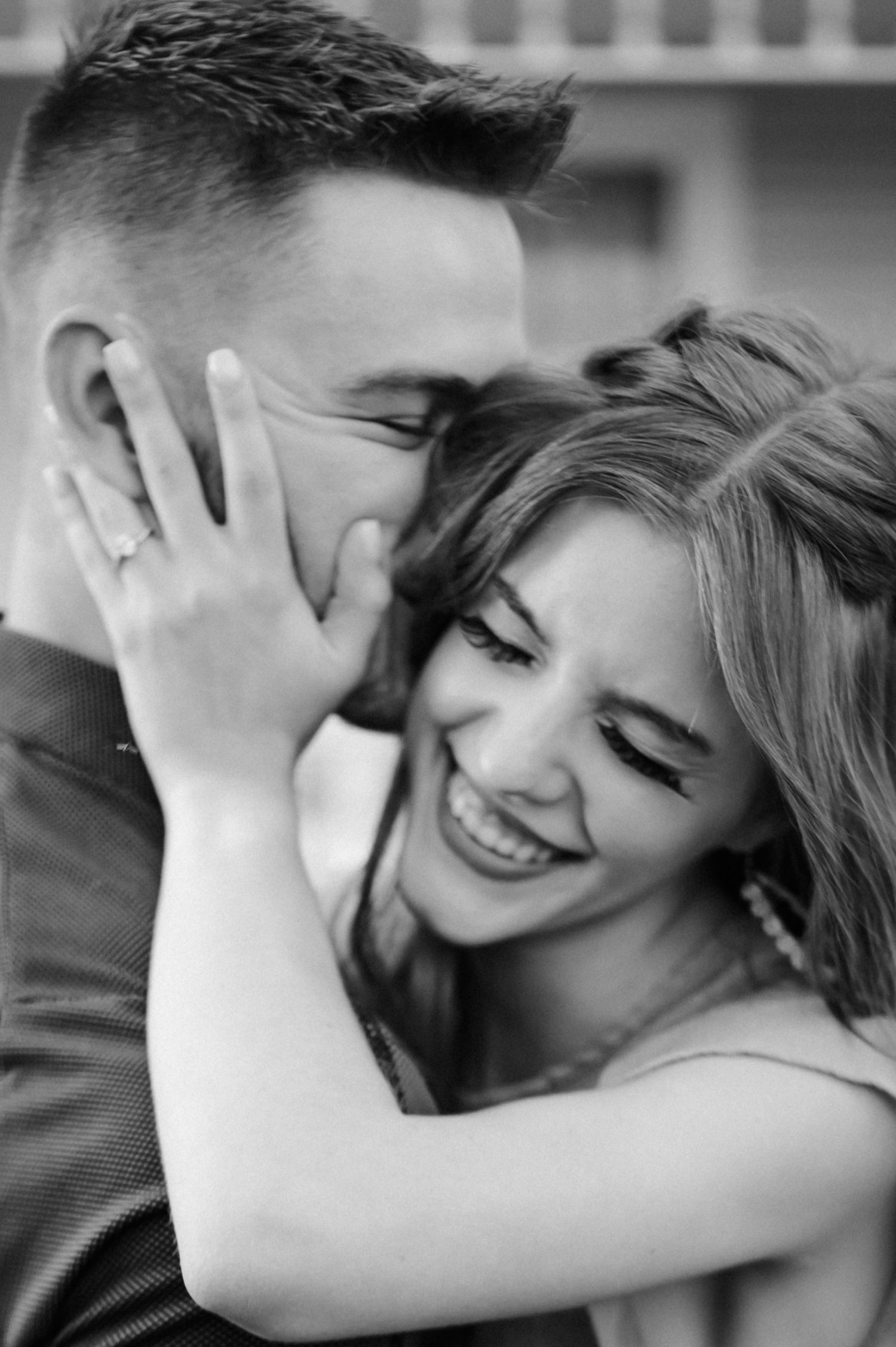 Intimate black and white portrait of engaged couple sharing a joyful moment.