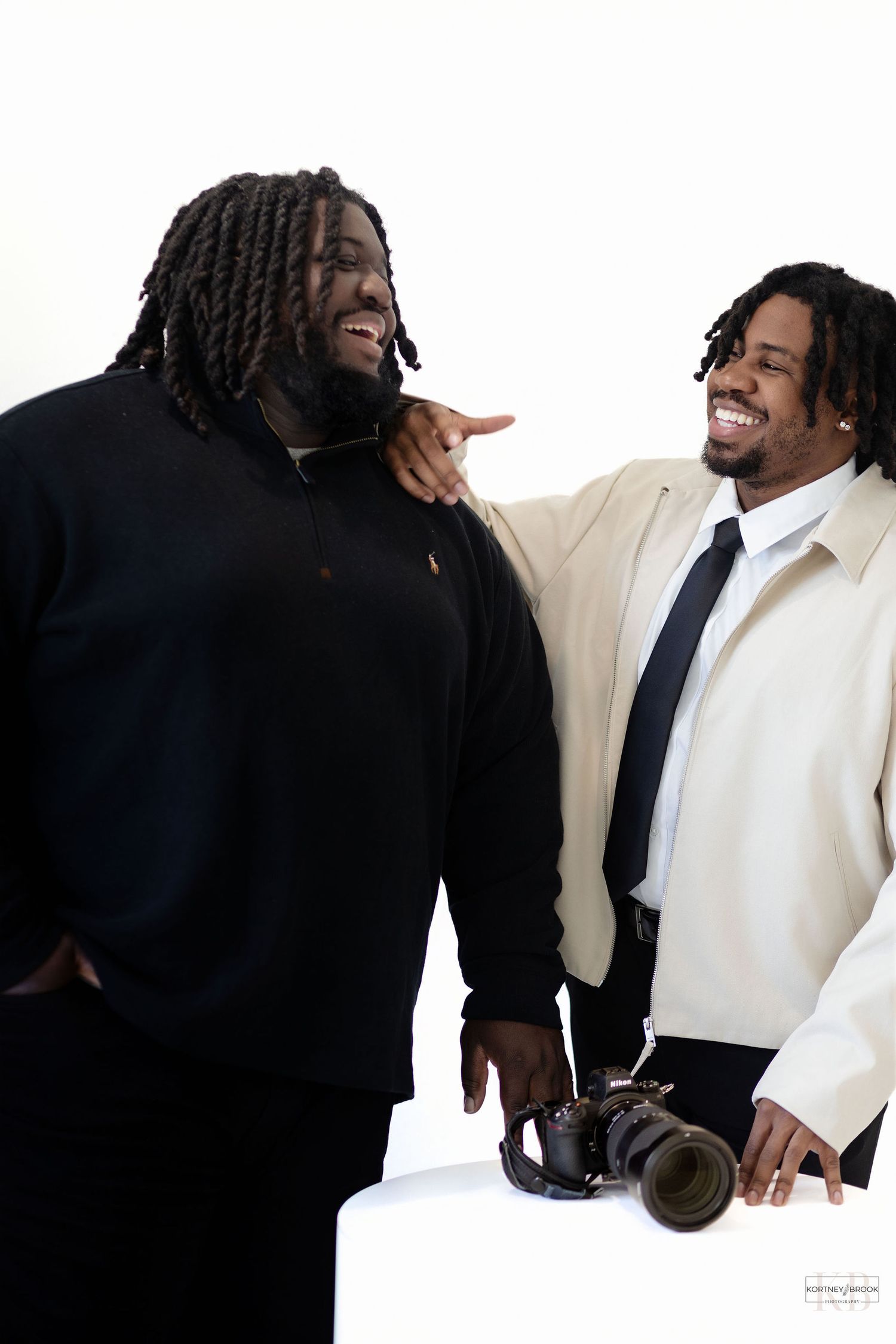 Two photographers sharing a candid laughing moment during a studio photoshoot.
