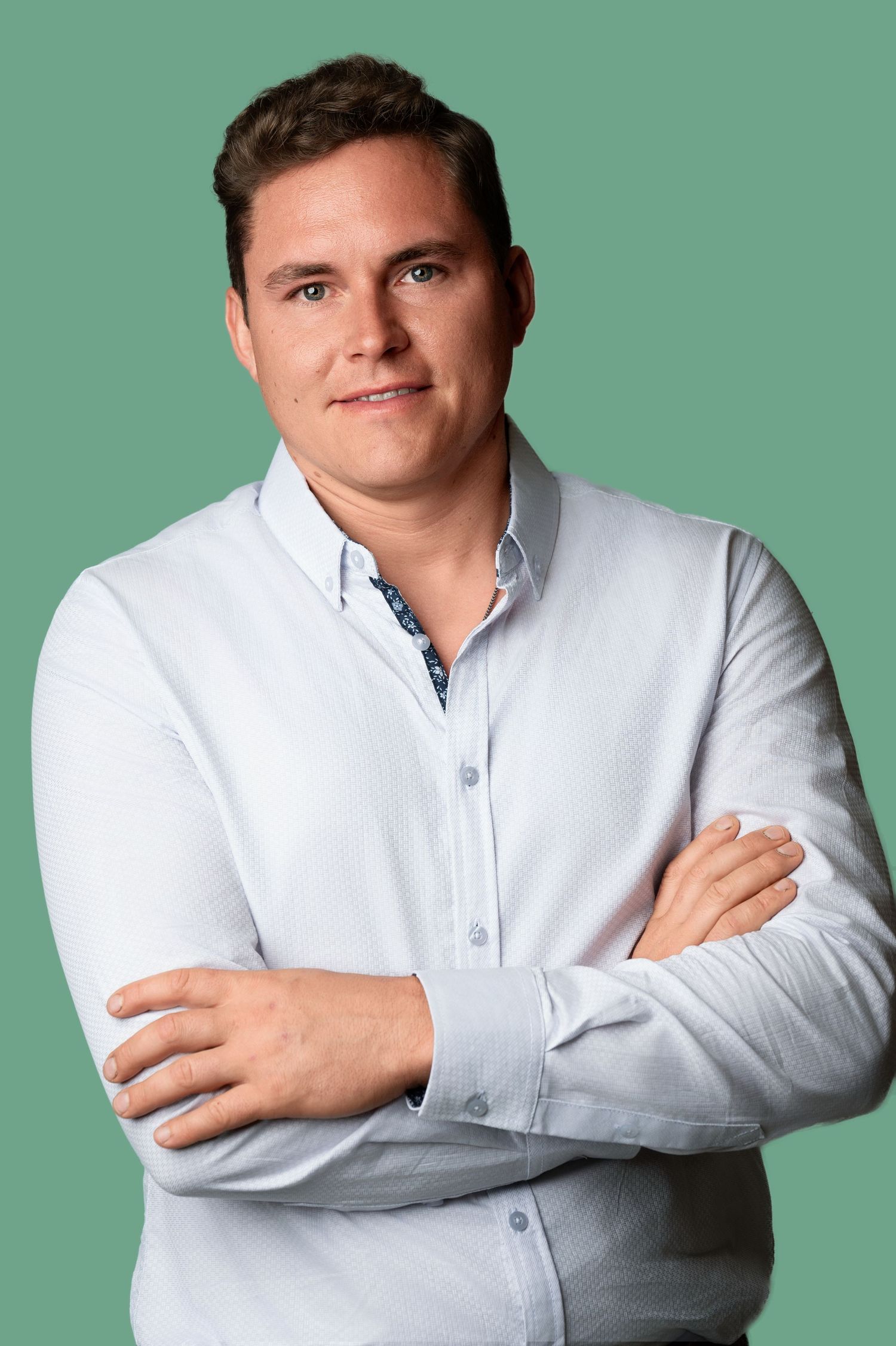 Professional headshot of person in white button-down shirt against green background.