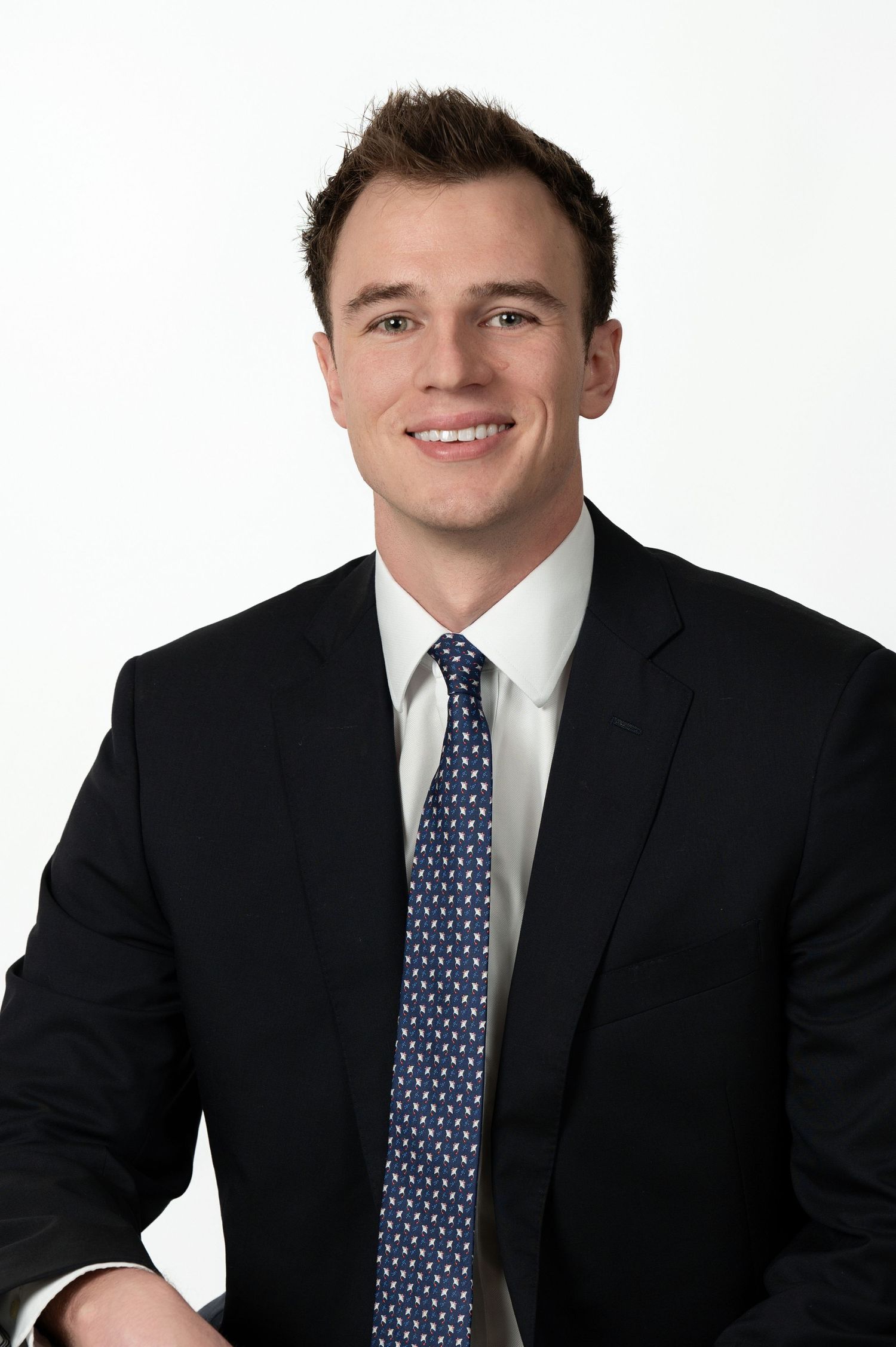 Professional headshot of person in dark suit with polka dot tie.