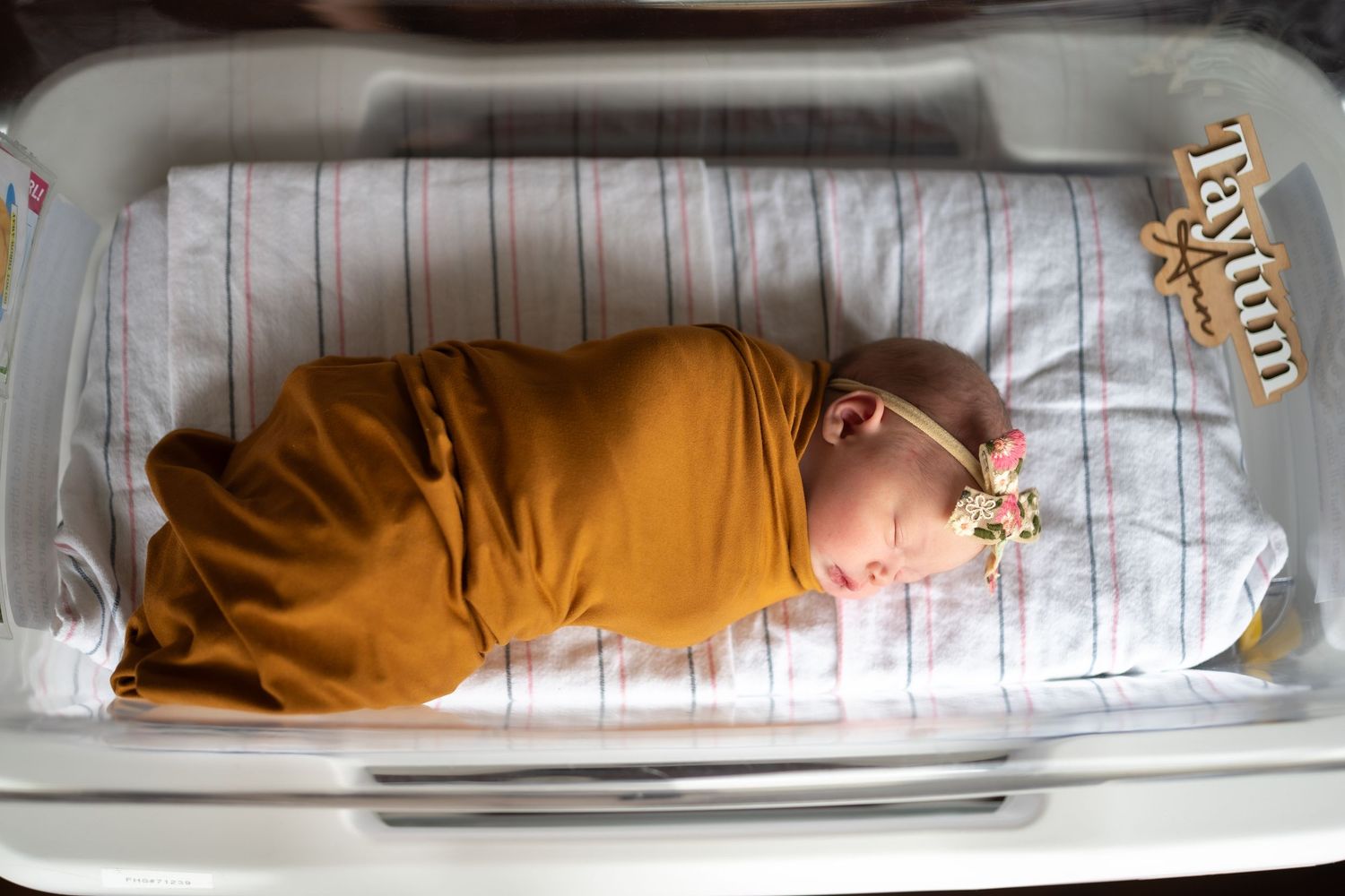 A sequence of images showing a baby sleeping peacefully in a brown swaddle on white striped bedding.