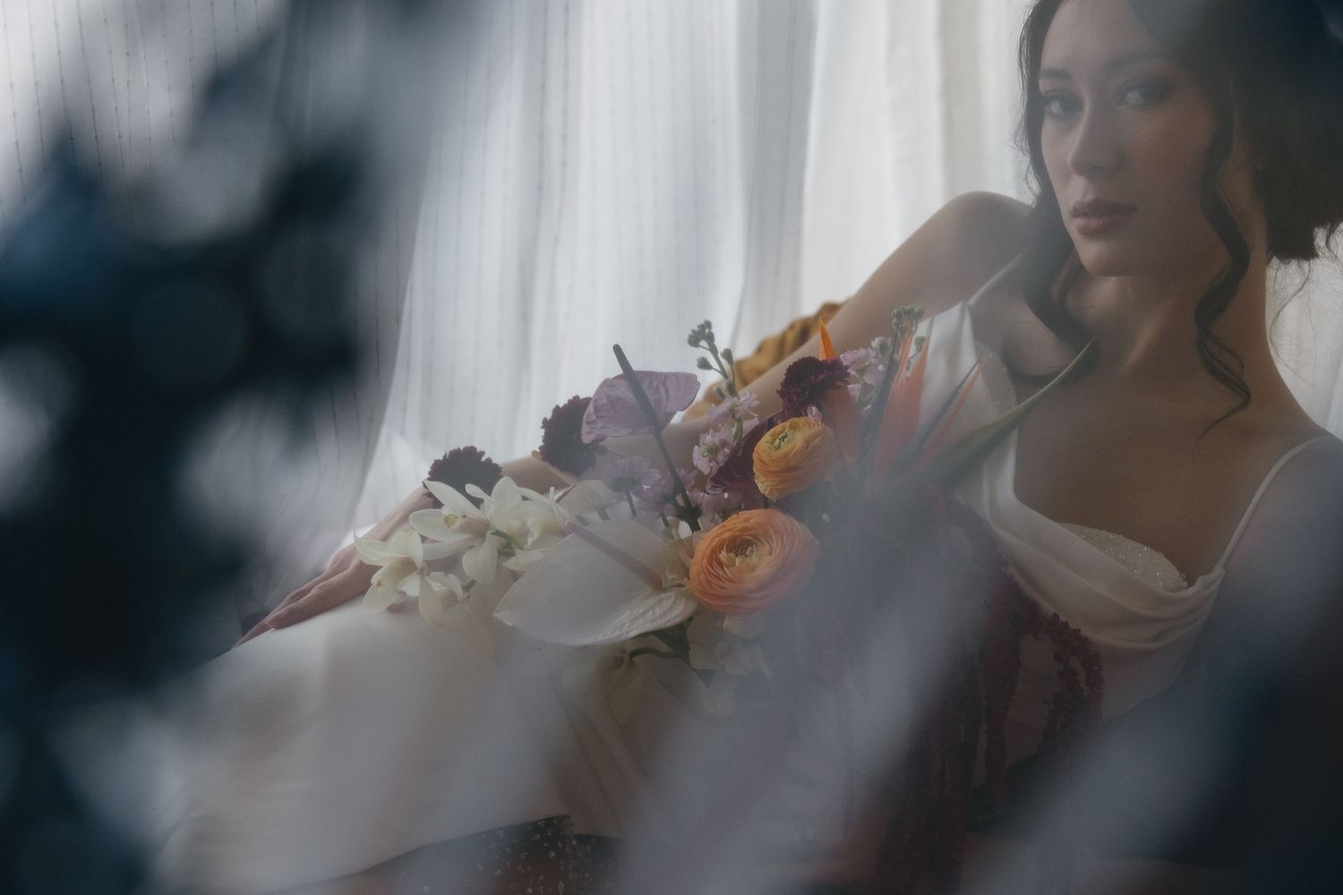 A person plays a violin while seated near a window with soft natural light streaming in.