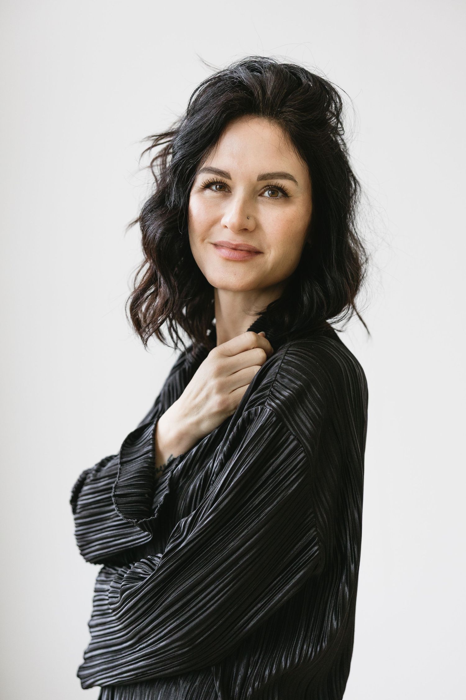 Four portrait shots of a woman with dark hair wearing a black turtleneck sweater against a light background.