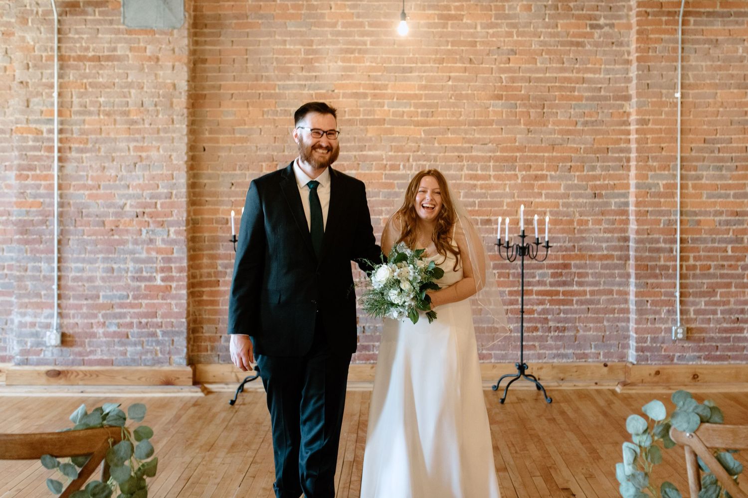 Bride and groom walking together after ceremony in industrial brick loft wedding venue.