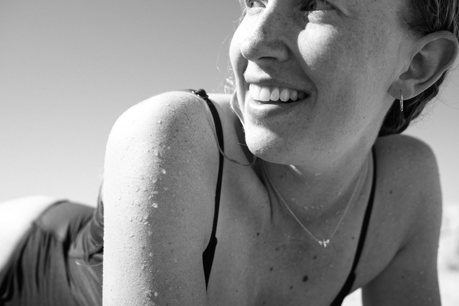 Black and white portrait of someone smiling in natural sunlight.