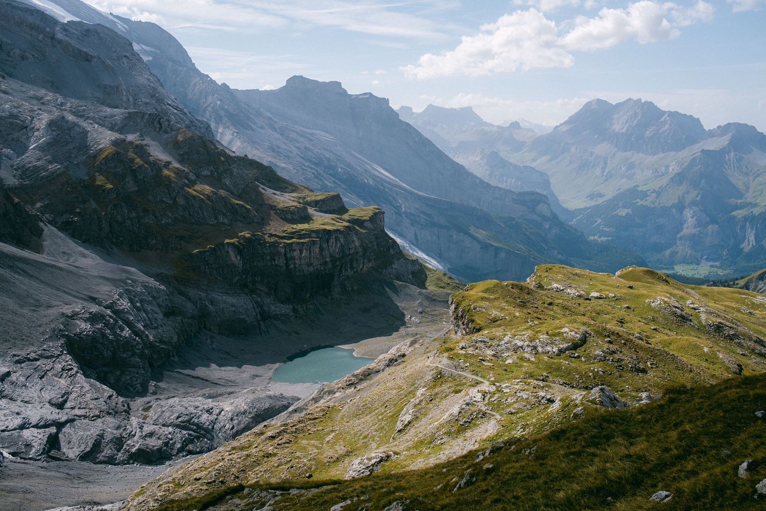 Dramatic mountain landscape with winding road and alpine lake in the Swiss Alps.