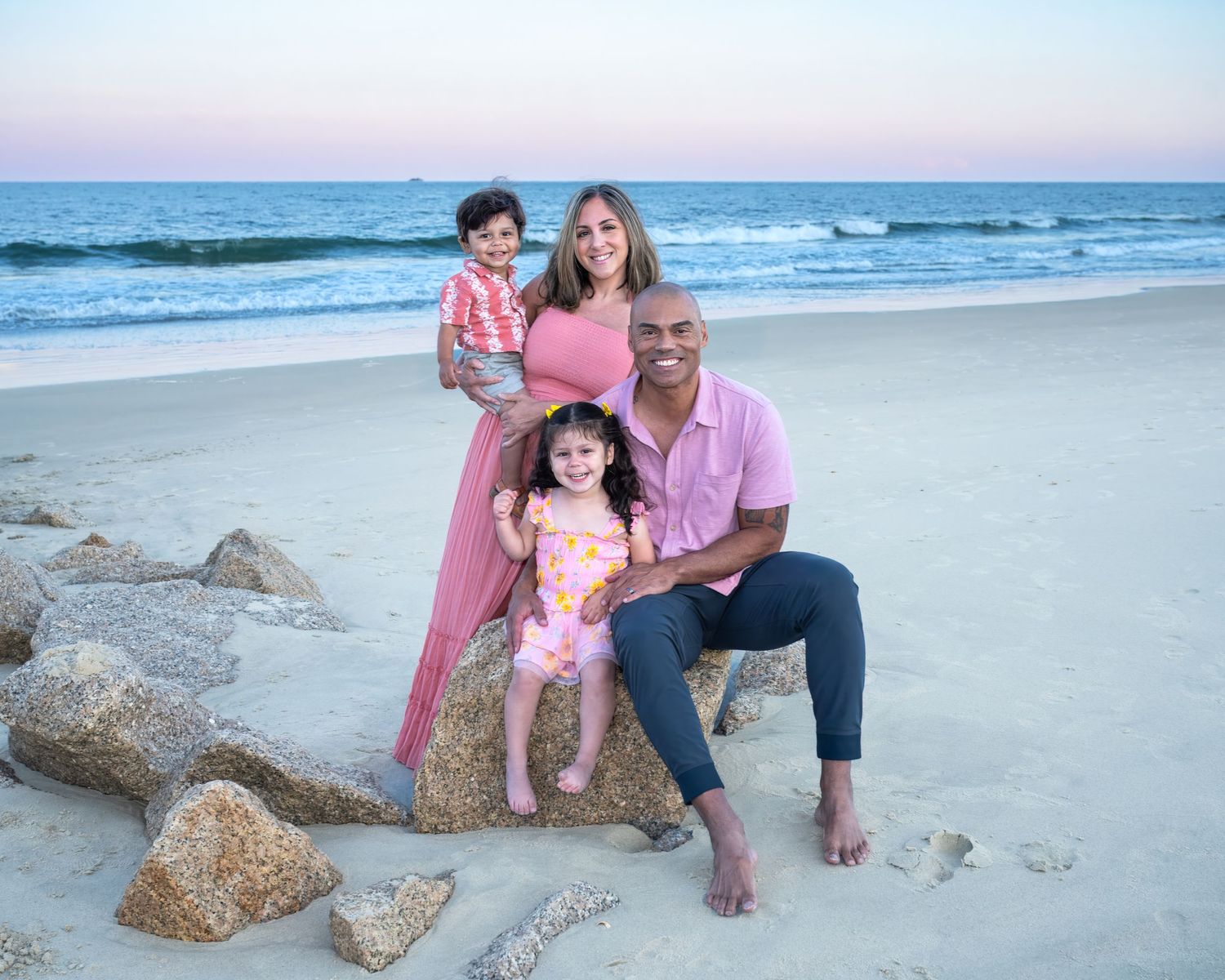 A group enjoying a relaxing evening on the beach at sunset while sitting on driftwood logs.