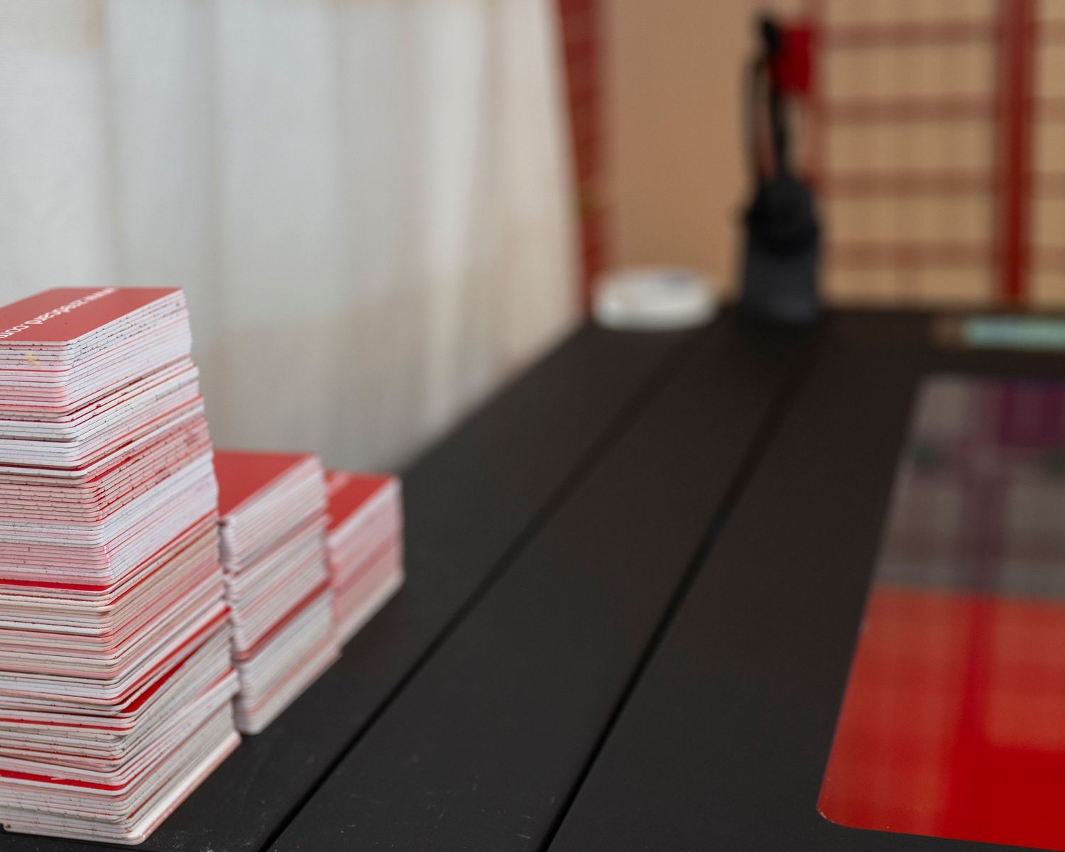 Two stacks of red and white playing cards on a black table with a blurred background.