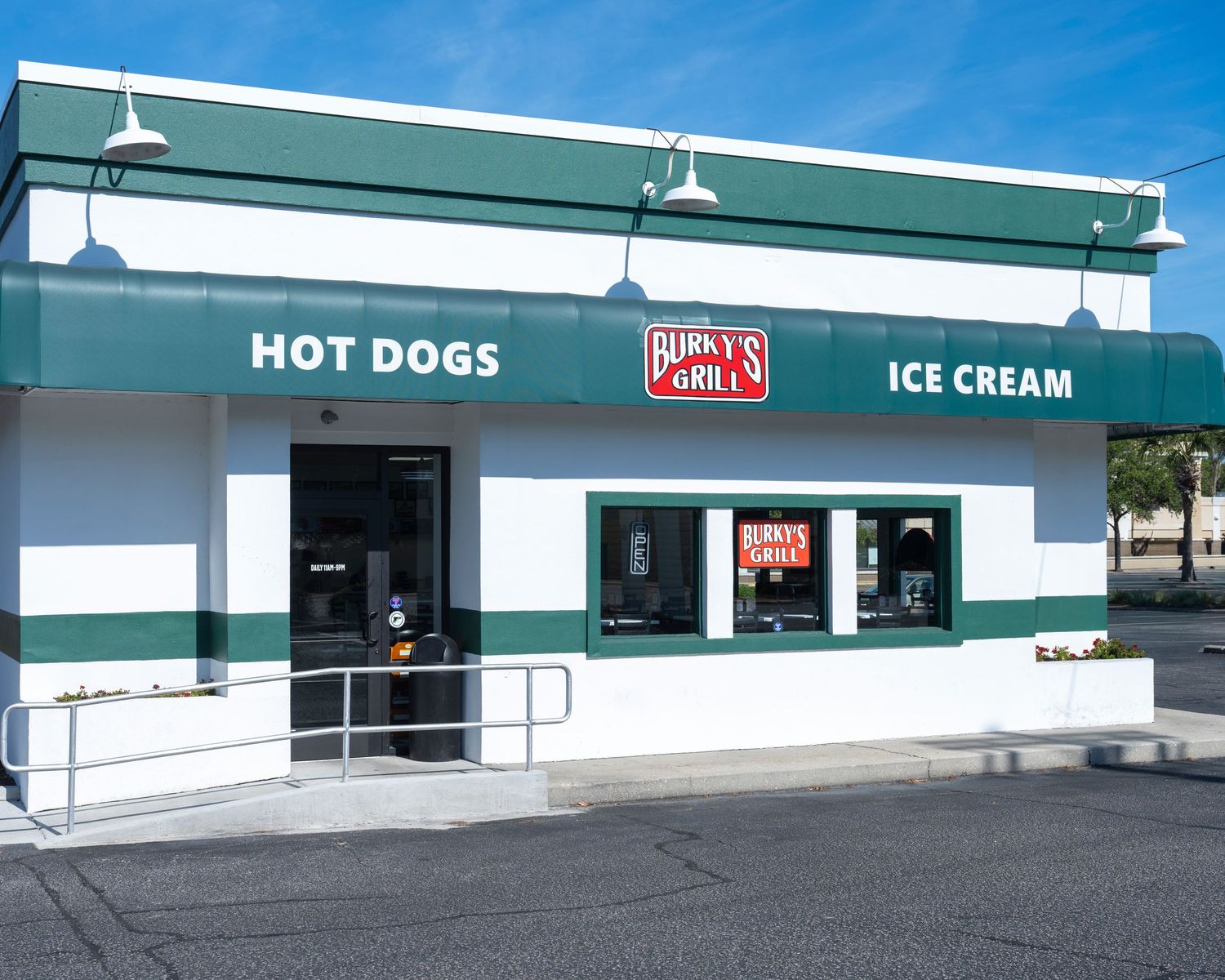 Burky's Grill exterior featuring hot dogs and ice cream signage on a green and white building with a drive-up window.