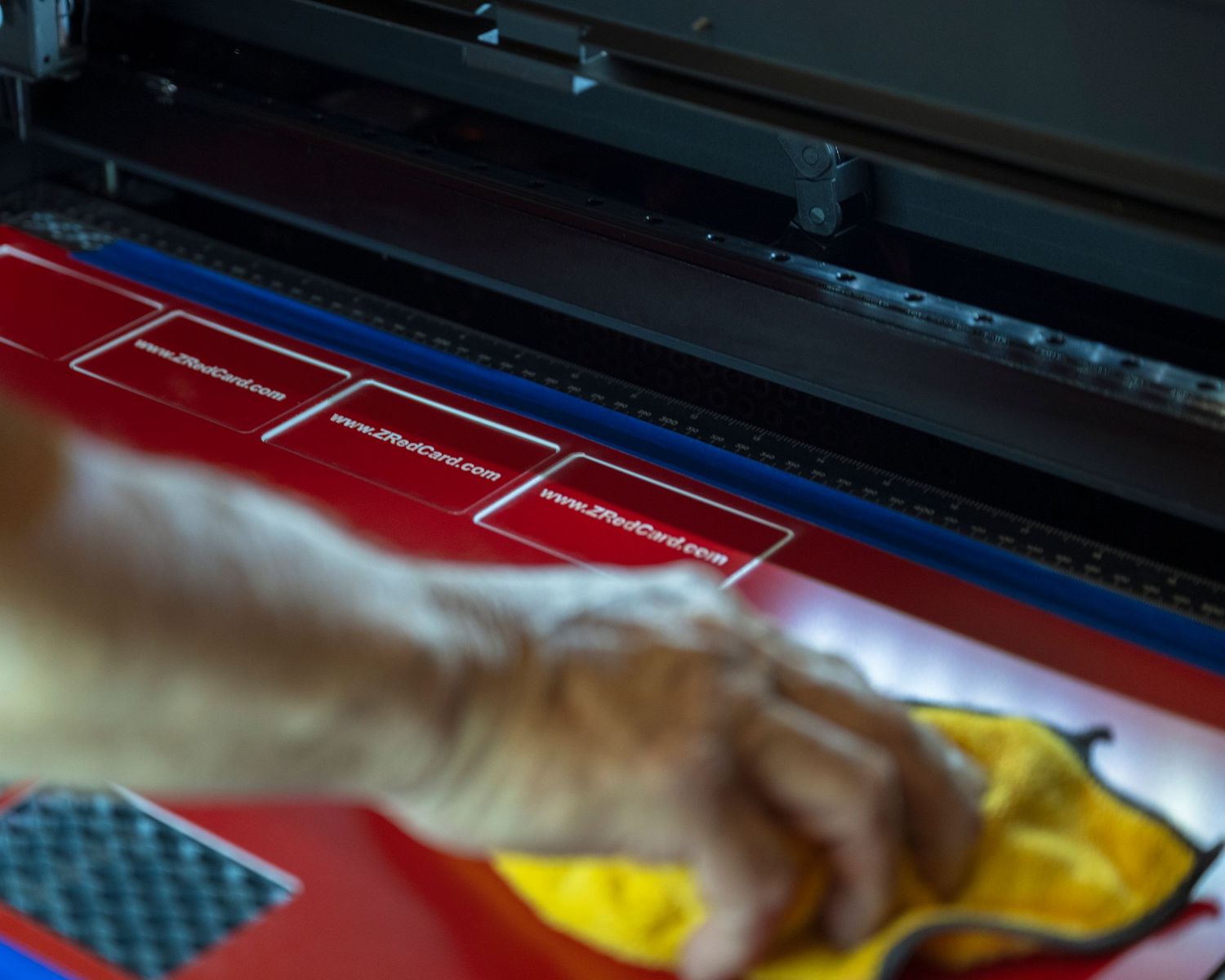 Close-up of a hand smoothing a vibrant red printed banner on a large format printing machine.