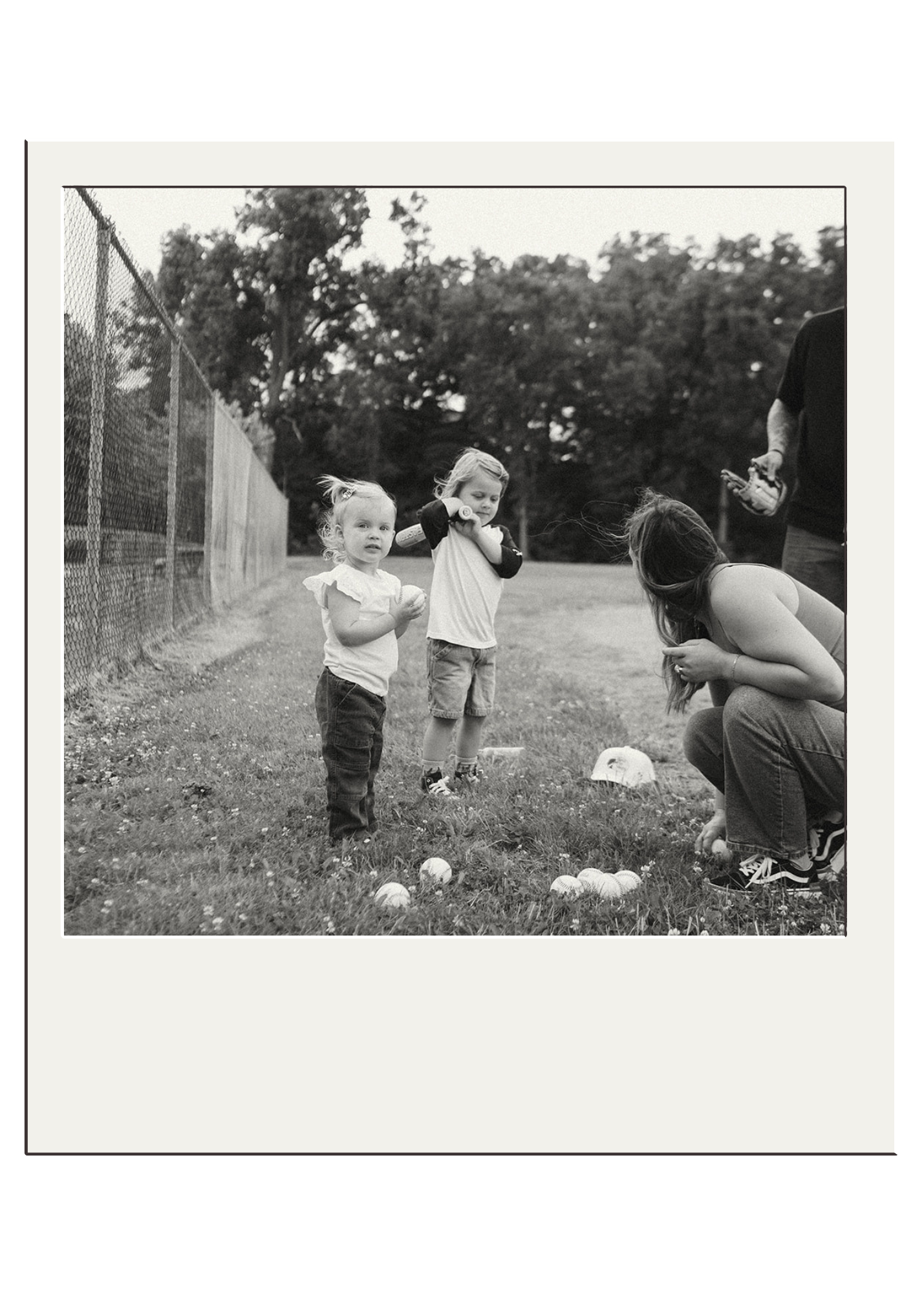 Black and white polaroid of children playing outdoors near a fence.