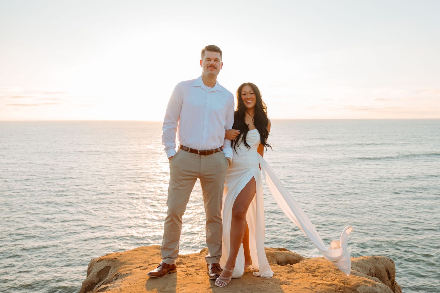 Romantic coastal sunset portrait on rocky oceanside cliff.