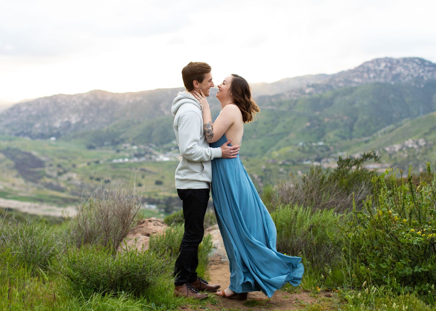 Romantic mountain scenery with flowing blue dress catching the wind.