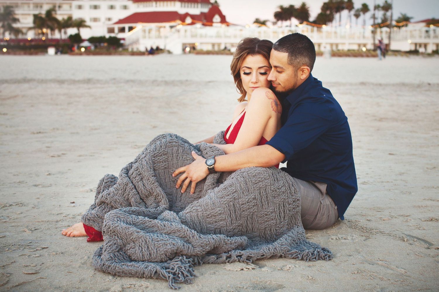 couple during engagement session cuddled up on the coronado beach.