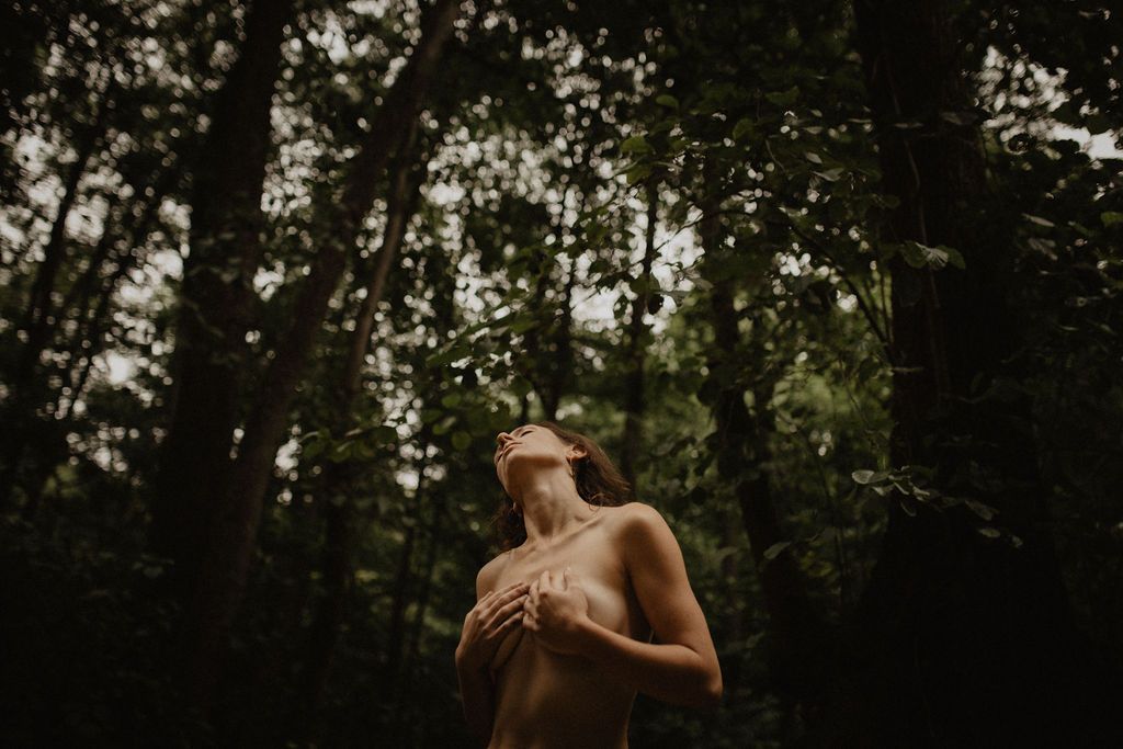 Artistic outdoor portrait in dusky forest with dramatic lighting and shadows.