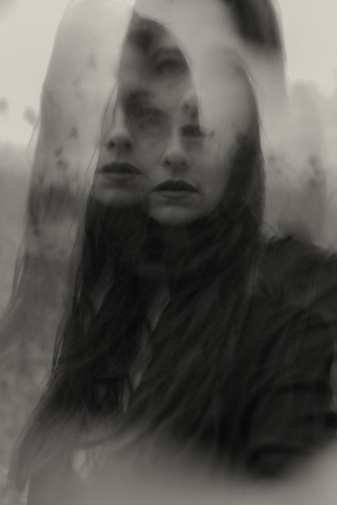 Double exposure portrait creating dreamy ethereal effect in black and white.