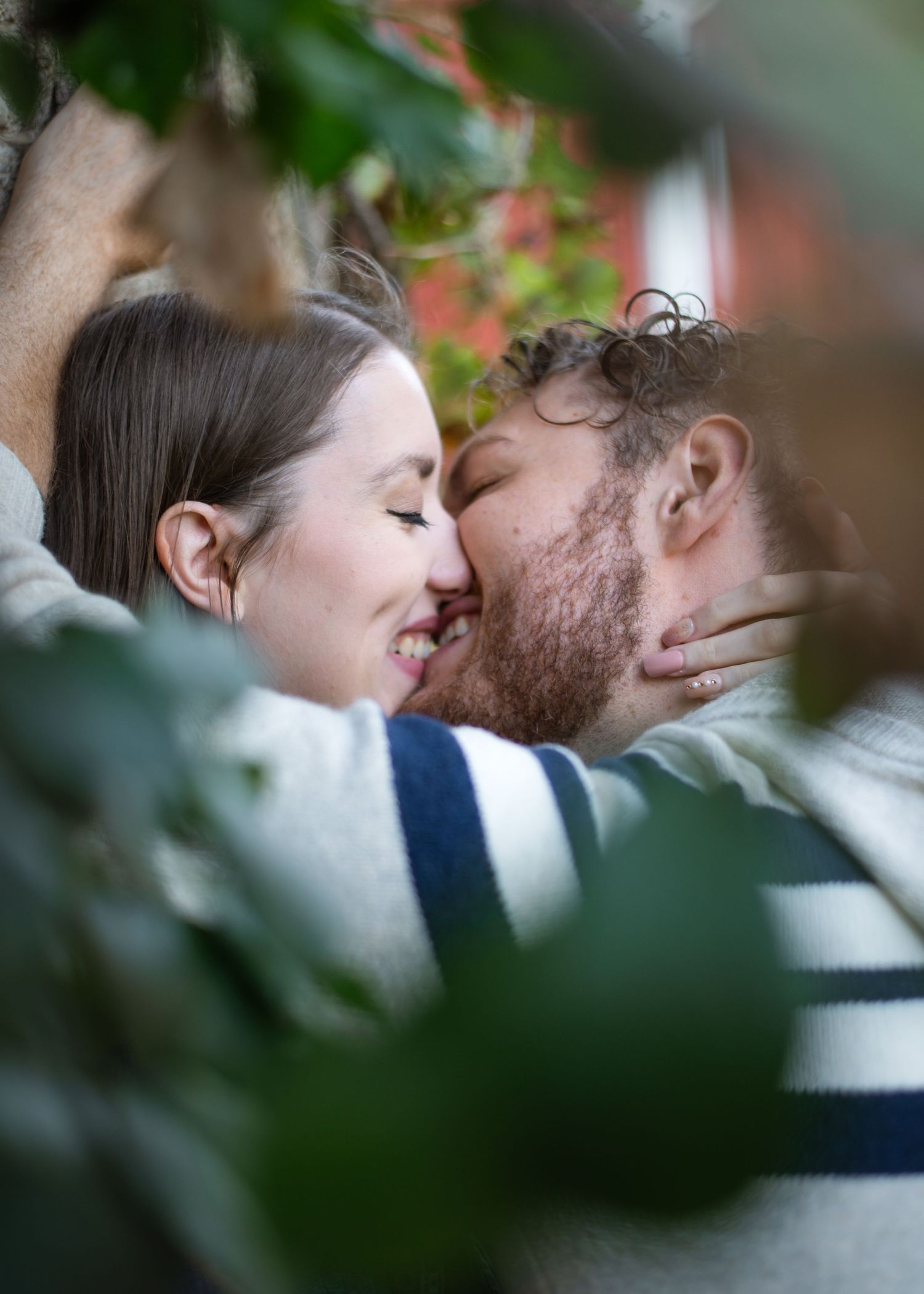 Intimate close-up of couple sharing tender moment among green foliage.