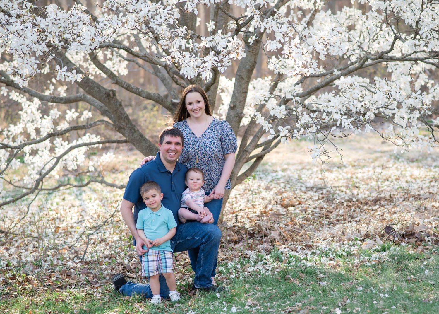 Family group portrait beside flowering tree in springtime.