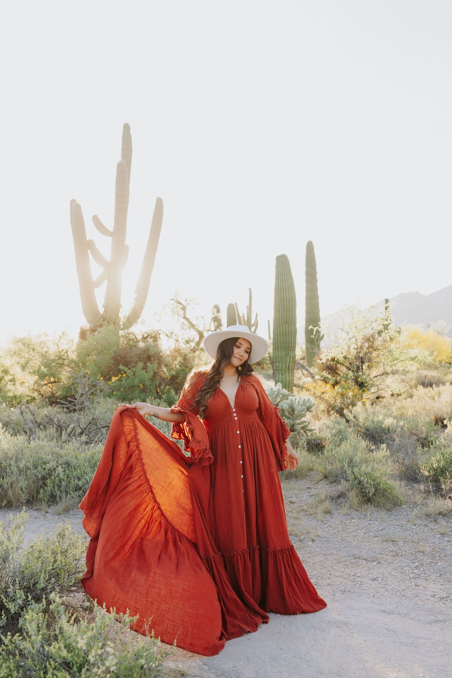 A flowing red dress twirls dramatically against a desert backdrop with towering saguaro cacti.