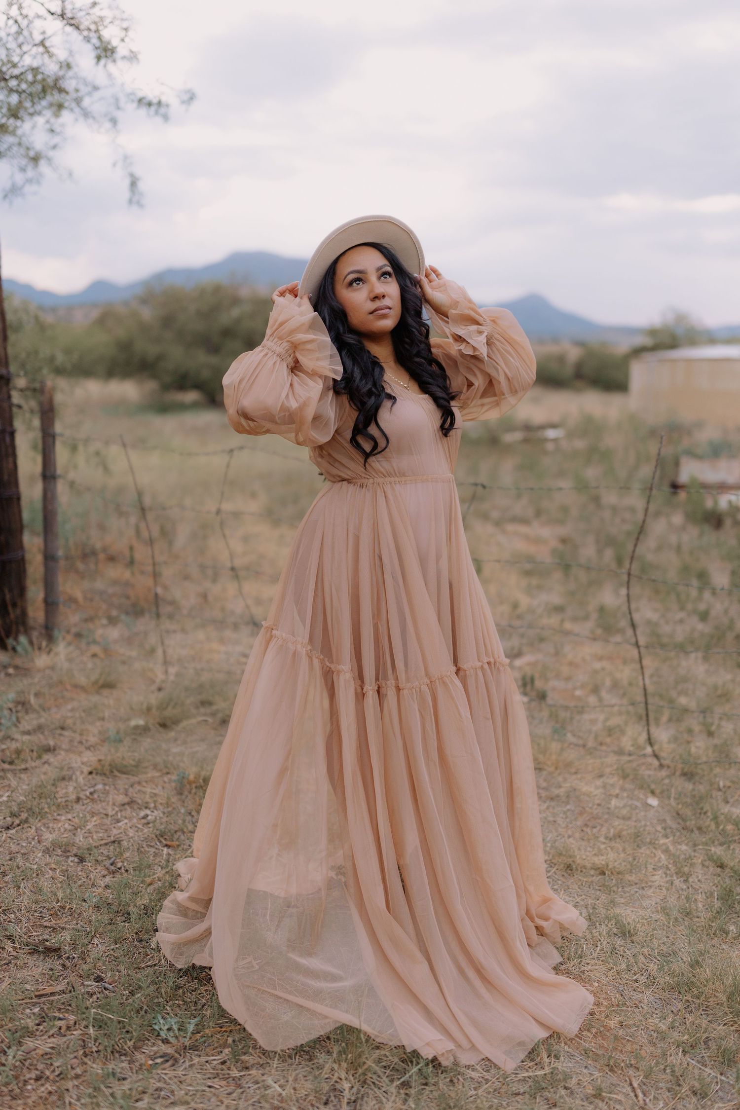A peachy pink dress flows in the desert breeze with mountains in the background.