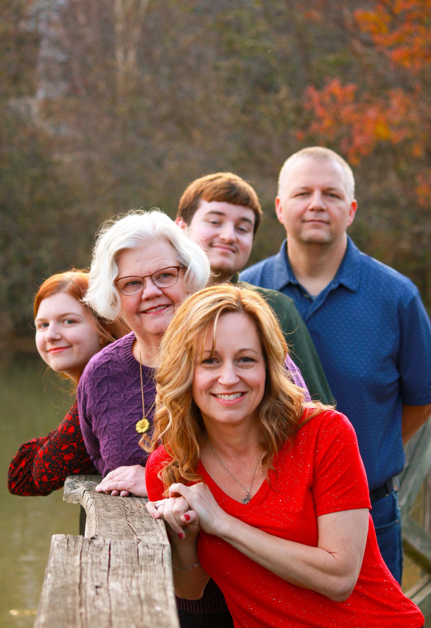 A family group poses casually together outdoors during golden hour in autumn.