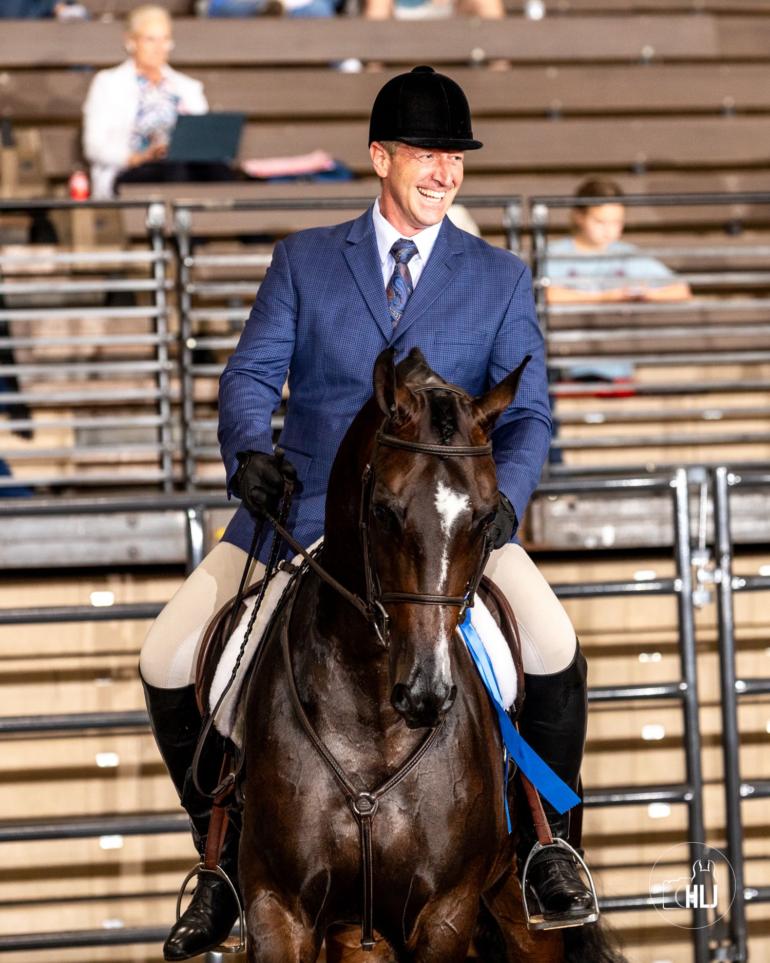 An equestrian rider in formal attire competes on a dark horse in a show ring.