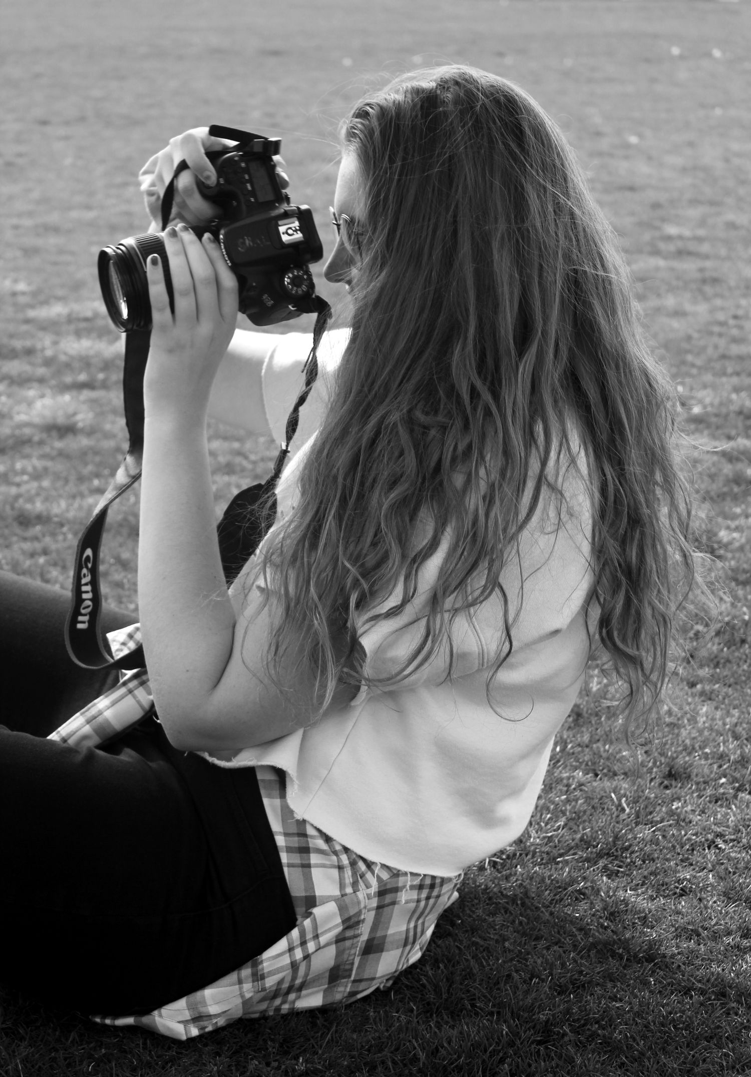 Black and white photo of photographer taking pictures outdoors in plaid pants.