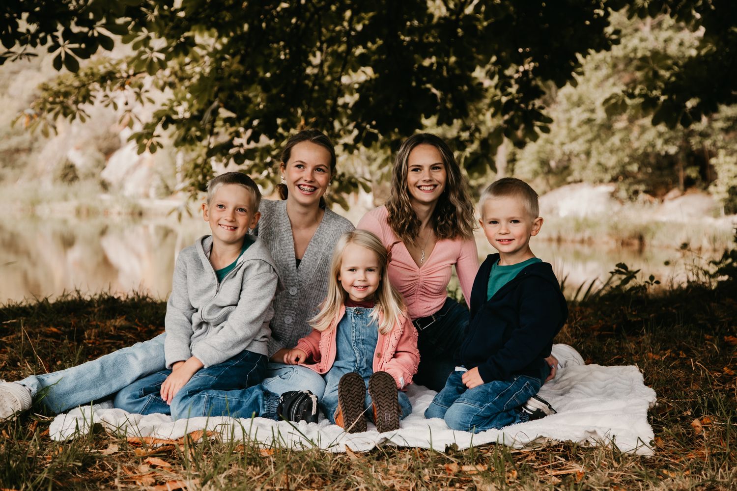 A family of five sitting on a blanket during a golden sunset photo session.