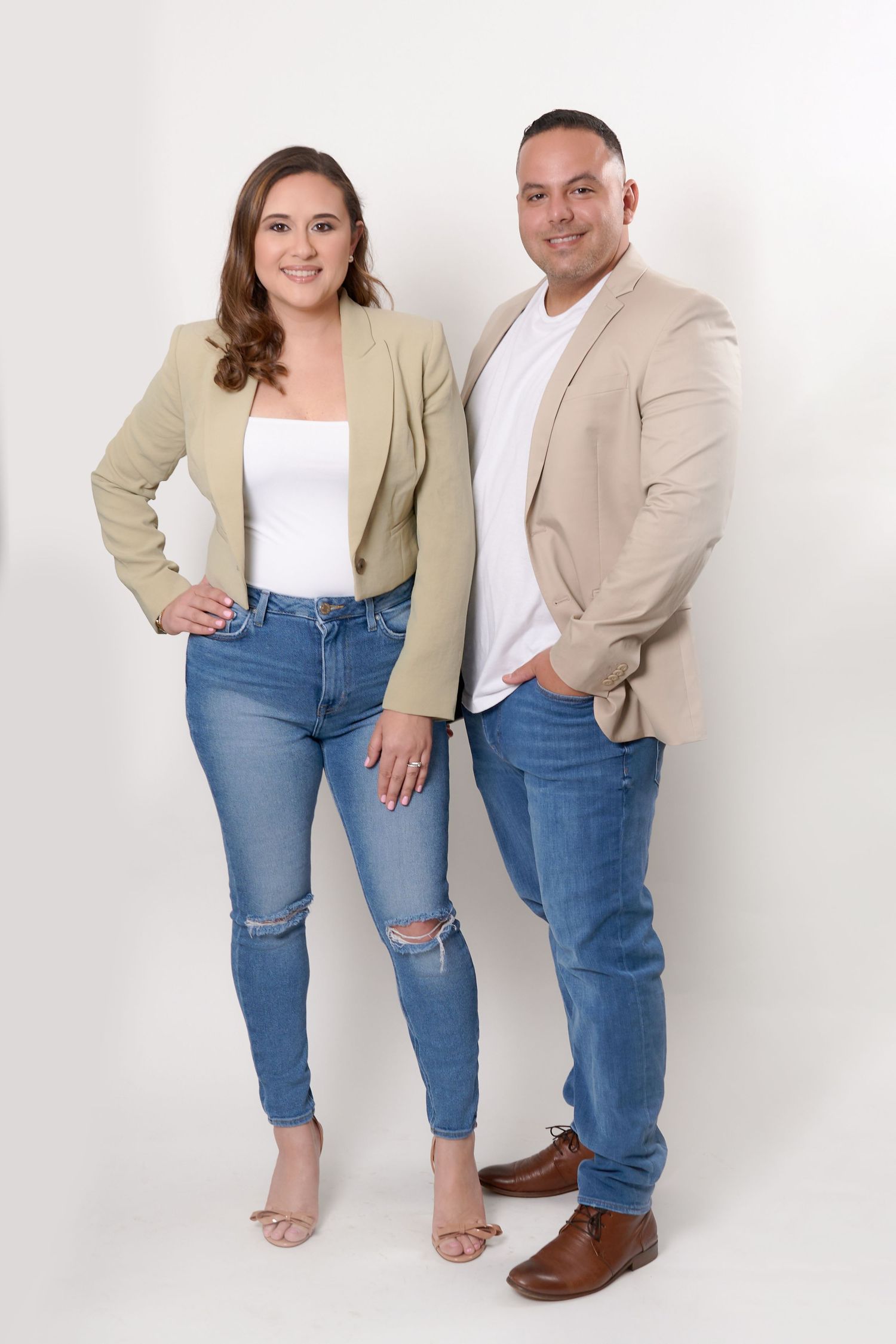 Studio portrait of a couple in coordinating casual business attire against white background.