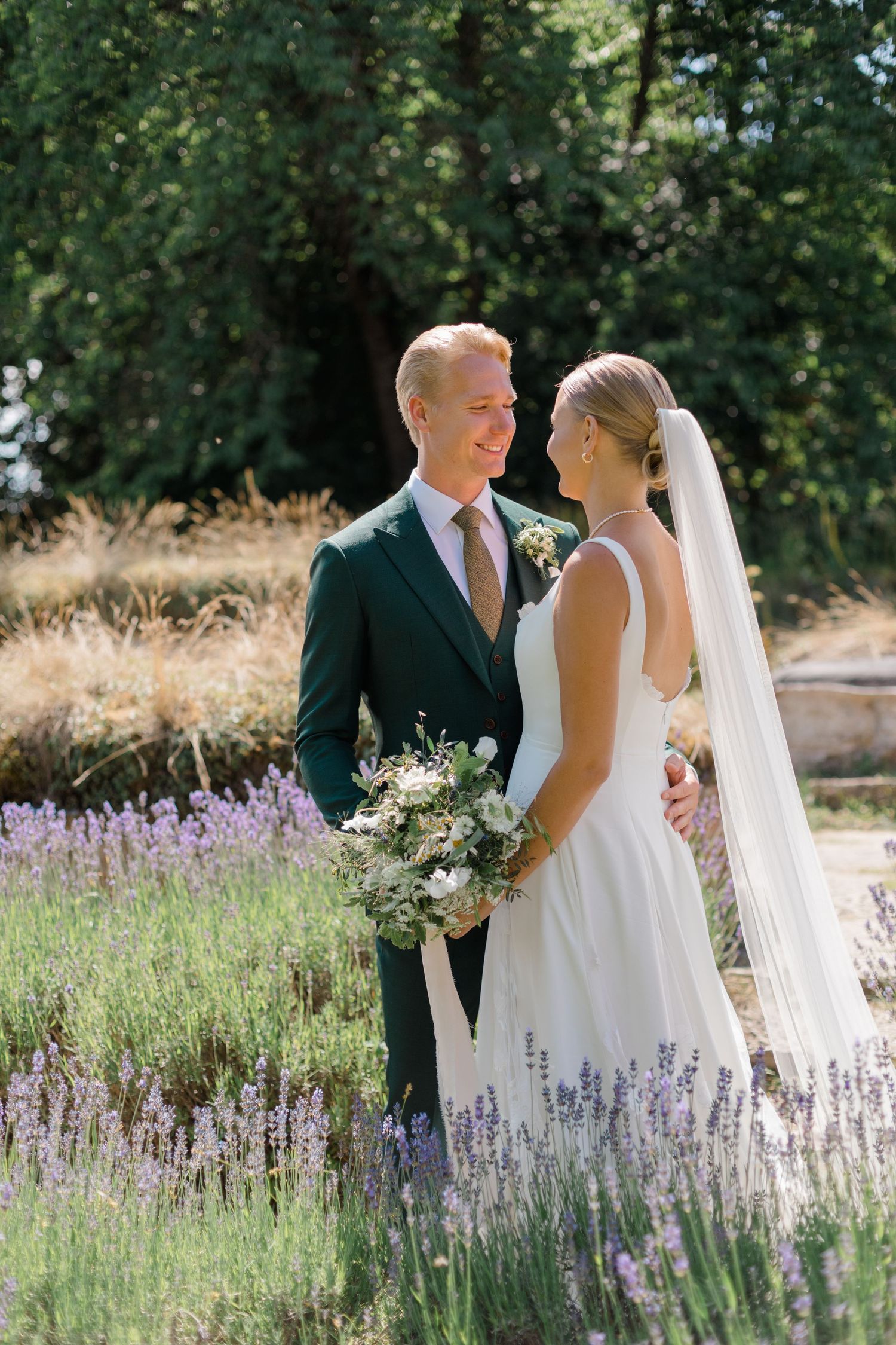 Elegant wedding couple standing together in a blooming lavender garden.
