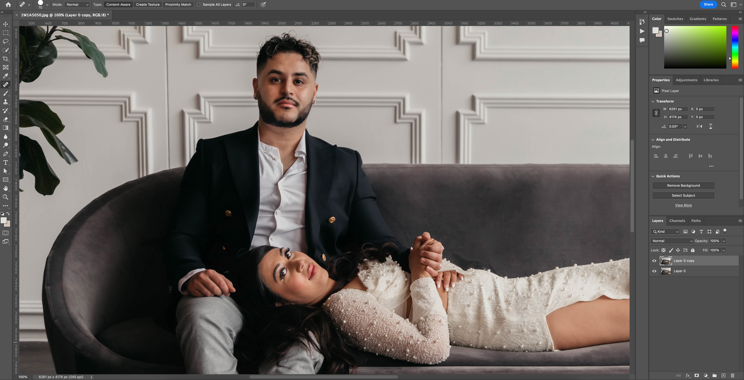 Couple posing on grey couch in studio with decorative wall panels.