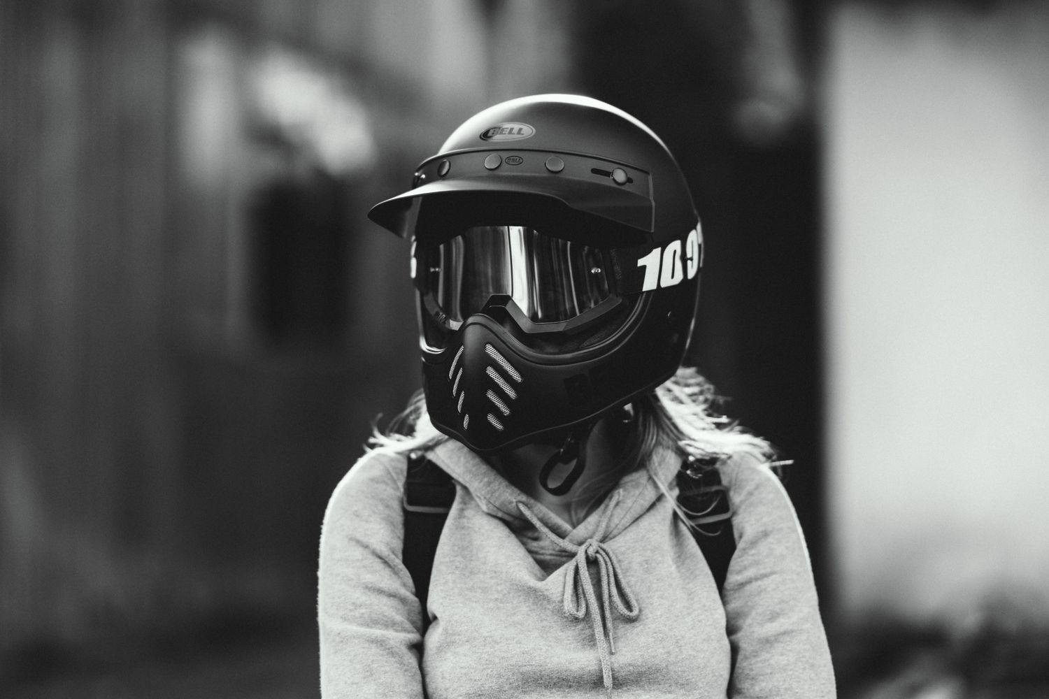 Person wearing protective paintball or motocross gear with a full face mask in black and white.