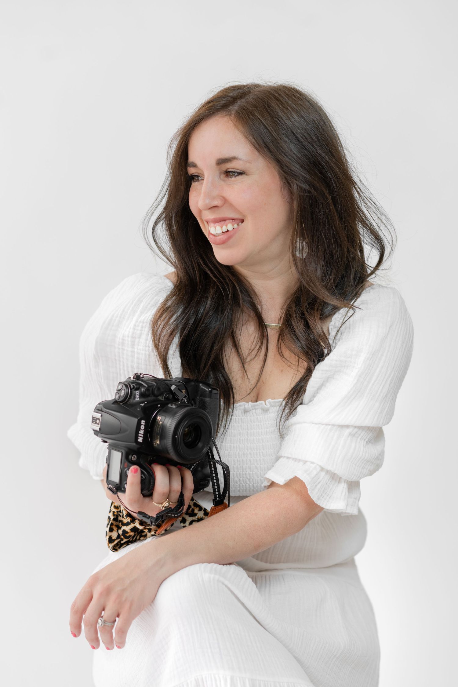 headshot of ashley line holding her camera and smiling over her right shoulder