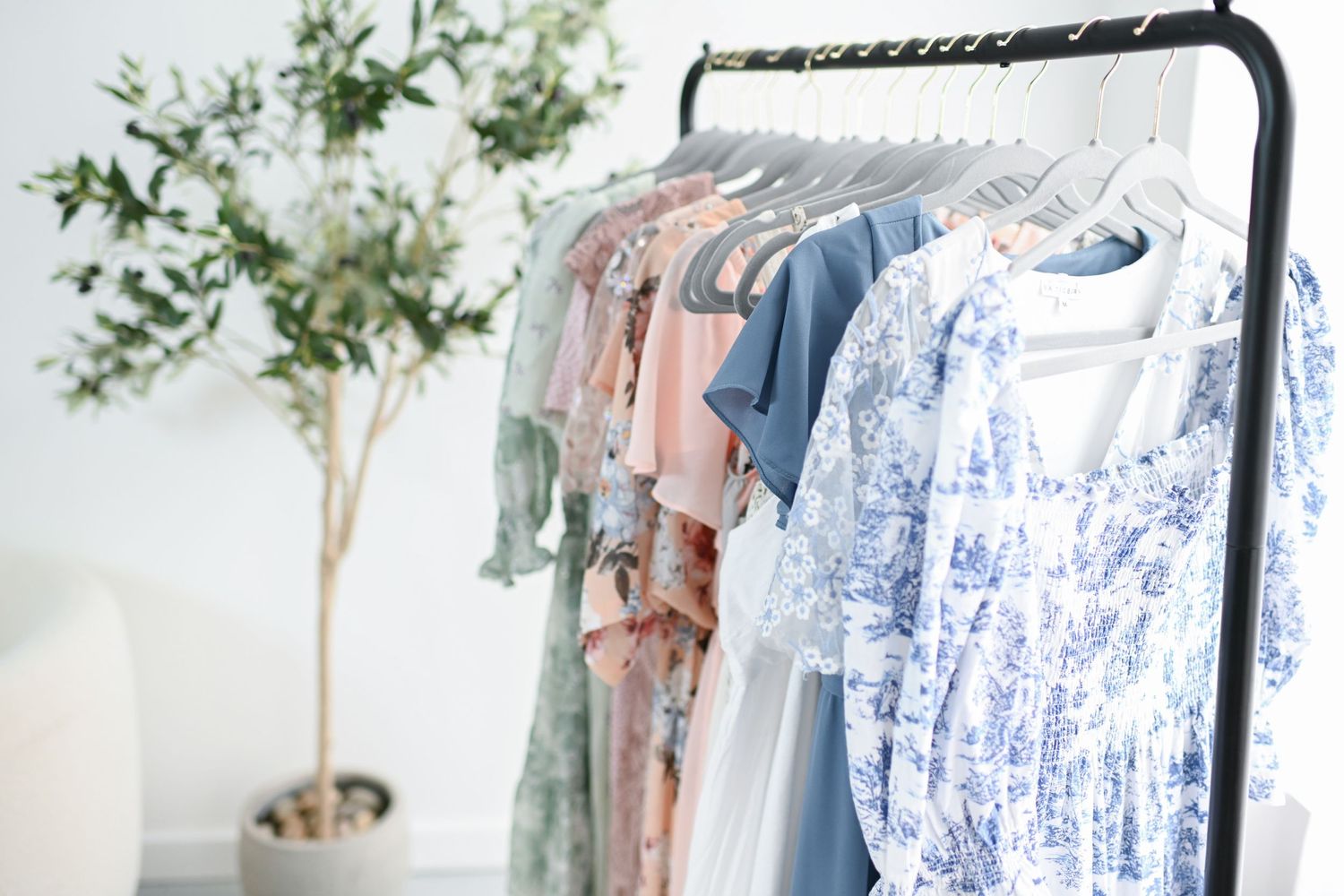 a photo of some of the motherhood dresses on a clothing rack with olive tree in the background