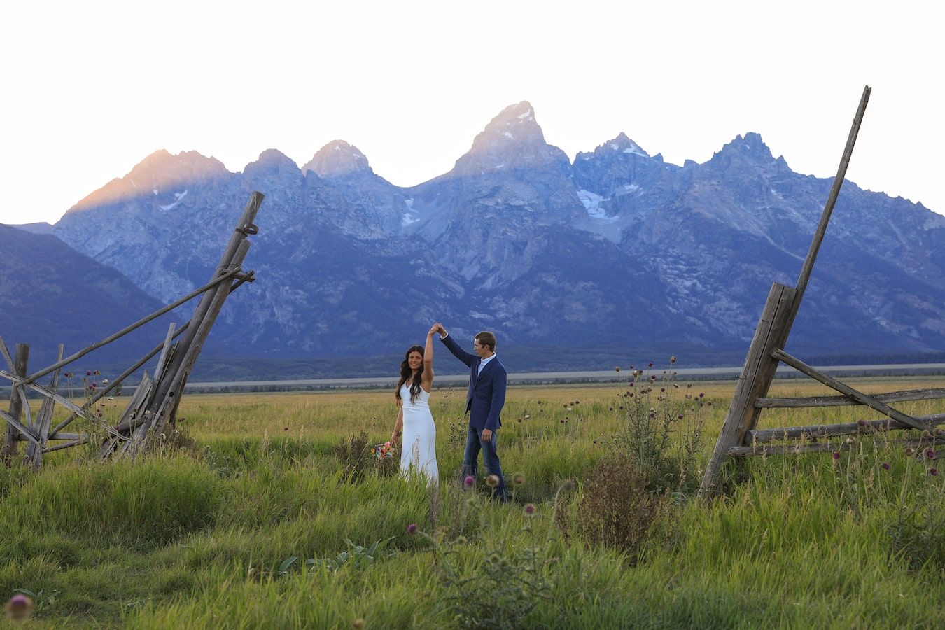 Hikers explore the grassy meadow beneath towering mountains in Grand Teton National Park.