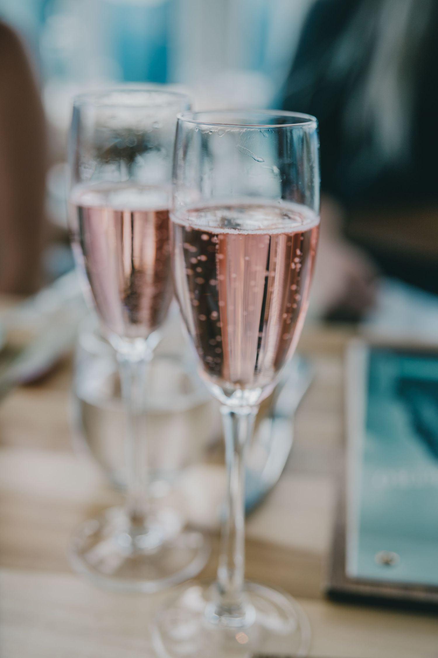 Two elegant champagne flutes filled with sparkling rose wine in soft focus.