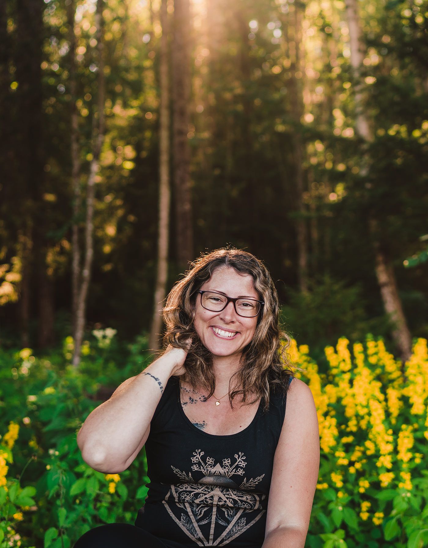 Självporträtt på fotograf Maria Karlsson en sommarkväll med gula blommor i bakgrunden
