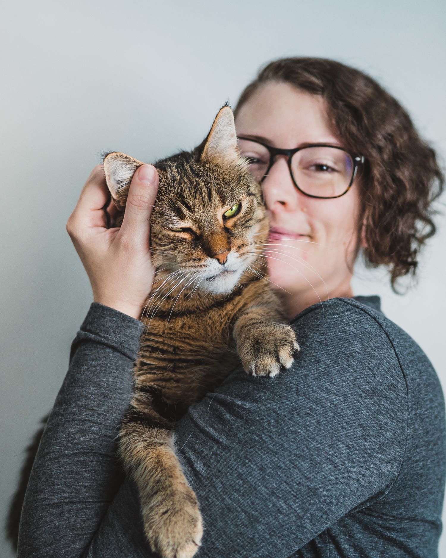 Fotograf Maria med sin katt Goliat kramas och tittar in i kameran med ett stort leende